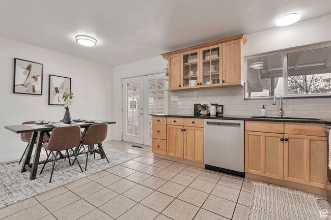 Kitchen featuring light tile patterned floors, decorative backsplash, dishwasher, and a sink | Image 11
