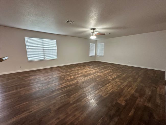 Empty room featuring dark wood finished floors, ceiling fan, and a textured ceiling | Image 5