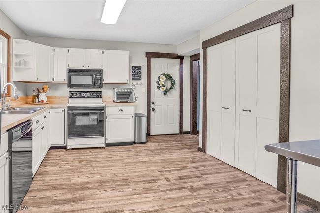 Kitchen featuring black appliances, white cabinetry, open shelves, and a sink | Image 18