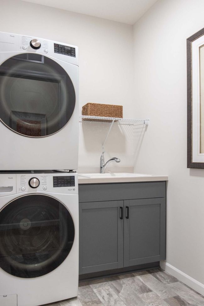 The main-level laundry room is both practical and efficient, featuring a stackable washer and dryer to save space, along with a convenient laundry sink for added functionality. Photos are from previously built home; options and features will vary. | Image 13