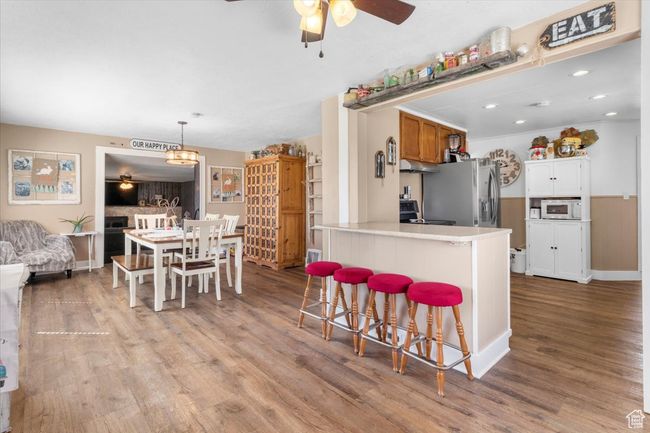 Kitchen with a kitchen bar, a peninsula, stainless steel appliances, light wood-style floors, and ceiling fan | Image 21