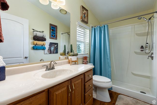 Bathroom featuring walk in shower, toilet, vaulted ceiling, vanity, and hardwood / wood-style flooring | Image 20