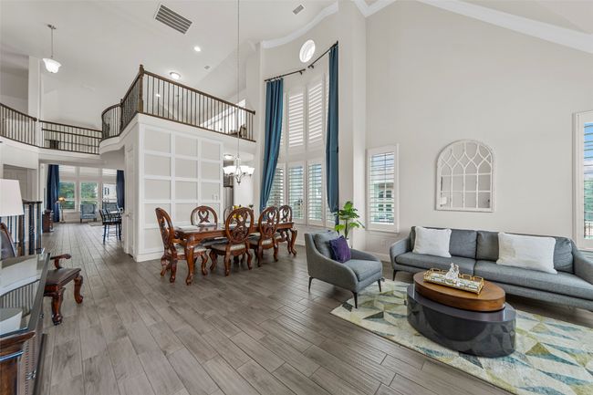 Living room featuring high vaulted ceiling, ornamental molding, wood finished floors, a chandelier, and baseboards | Image 7