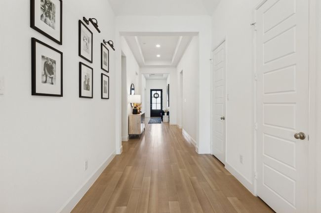 Hallway featuring a raised ceiling, light wood-style flooring, baseboards, and recessed lighting | Image 34