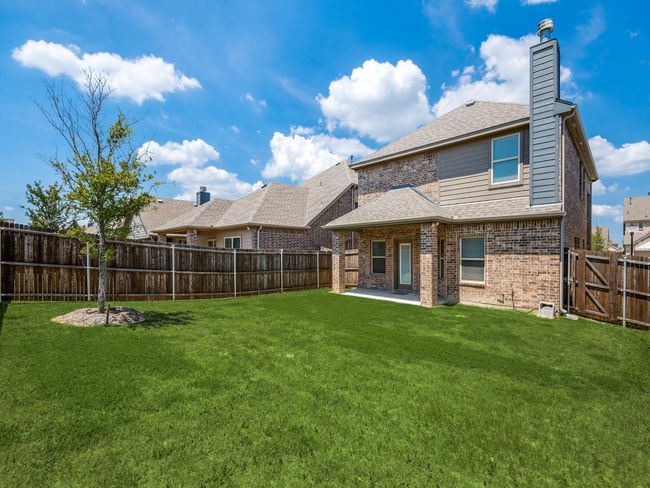 Rear view of house featuring a patio area, a fenced backyard, a yard, and brick siding | Image 12