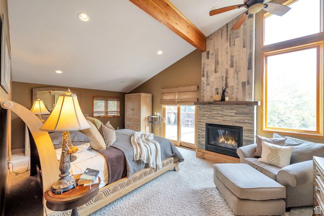 Carpeted bedroom featuring beam ceiling, a large fireplace, recessed lighting, and access to exterior | Image 30