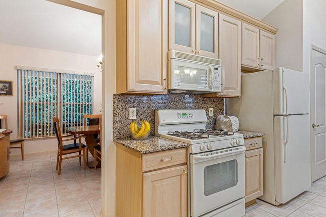 Kitchen with light tile patterned floors, light brown cabinetry, and white appliances | Image 31