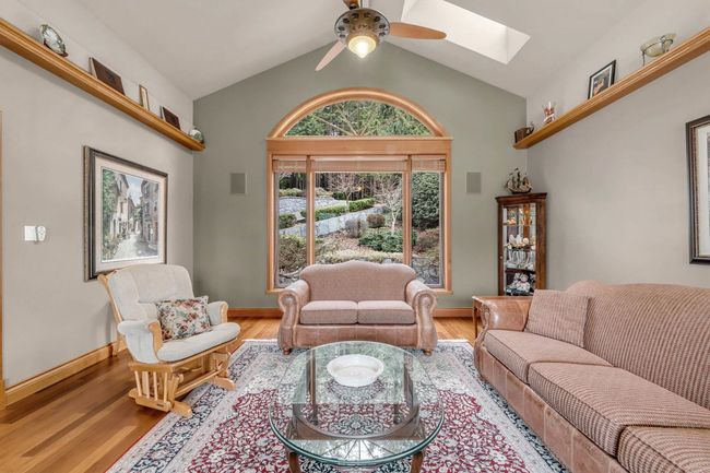Living room with vaulted ceiling with skylight, wood finished floors, and ceiling fan | Image 14