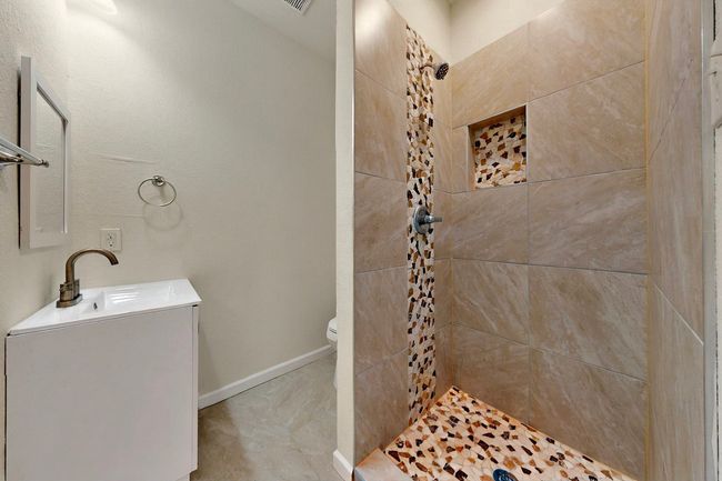 Full bathroom with tiled shower, toilet, vanity, and baseboards | Image 9