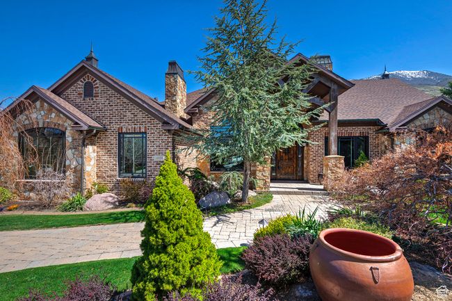 View of front of property featuring a chimney, a shingled roof, stone siding, and brick siding | Image 68