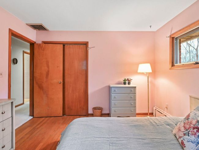 Bedroom featuring a baseboard heating unit, light hardwood / wood-style flooring, and a closet | Image 24