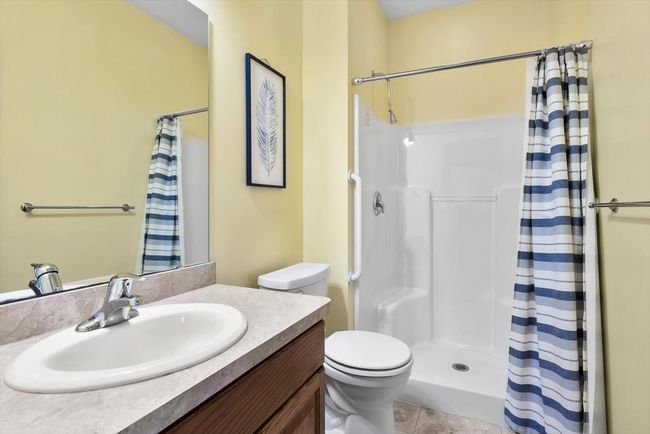 Bright and airy bathroom featuring a walk-in shower with a safety handle for added comfort and accessibility. | Image 23
