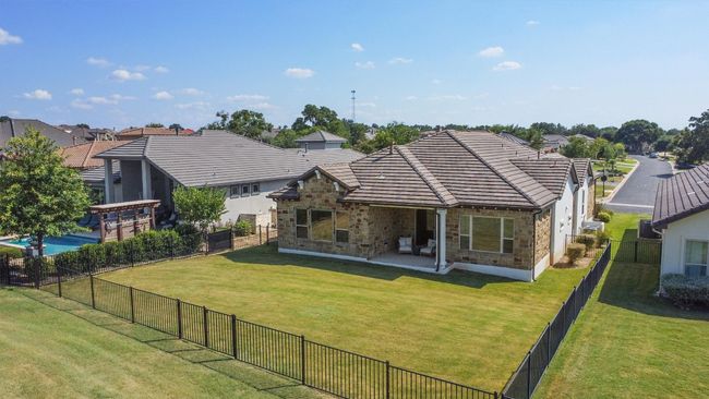 Back of property with stone siding, a tile roof, a fenced backyard, and a patio area | Image 39