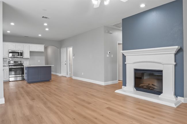 Unfurnished living room with arched walkways, light wood-style floors, recessed lighting, baseboards, and ceiling fan | Image 12
