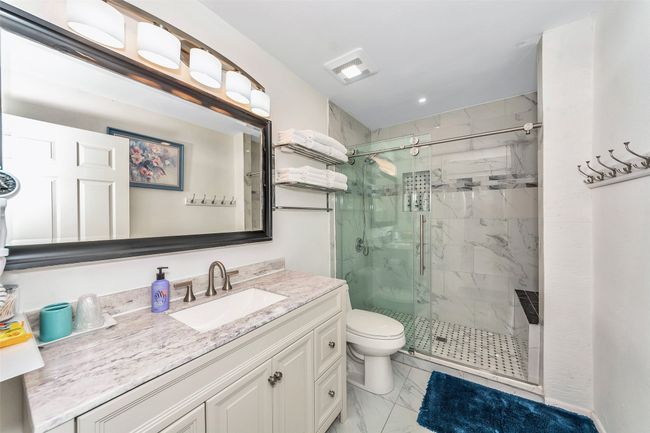 Full bathroom featuring marble look tile flooring, a marble finish shower, toilet, and vanity | Image 15