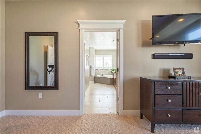 Bedroom with baseboards, connected bathroom, light tile patterned floors, and light carpet | Image 33