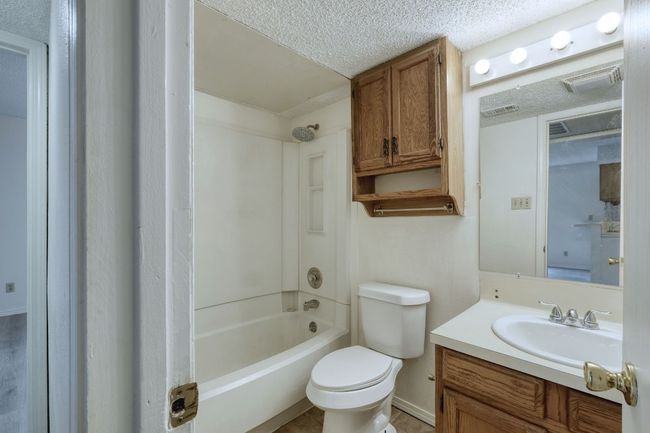 Bathroom with a textured ceiling, vanity, and shower combination | Image 5