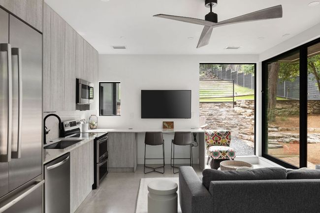 Kitchen with modern cabinets, stainless steel appliances, a sink, concrete flooring, and a ceiling fan | Image 32
