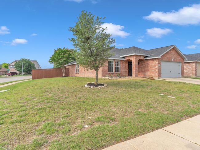 Ranch-style home featuring brick siding, an attached garage, driveway, a front yard, and roof with shingles | Image 33