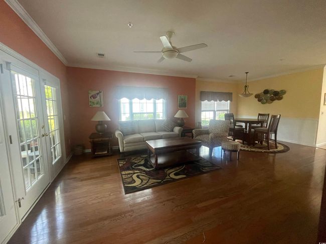 Living area featuring ornamental molding, a ceiling fan, wood finished floors, and visible vents | Image 6