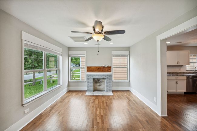 Unfurnished living room with a fireplace, dark wood-type flooring, ceiling fan, and recessed lighting | Image 4