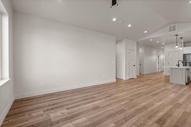 Unfurnished living room featuring visible vents, lofted ceiling, light wood-style floors, and baseboards | Image 12