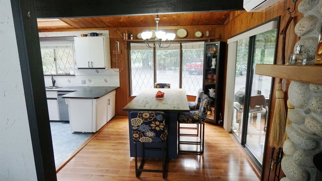 Kitchen featuring a center island, pendant lighting, dark countertops, light wood-style flooring, and white cabinets | Image 4