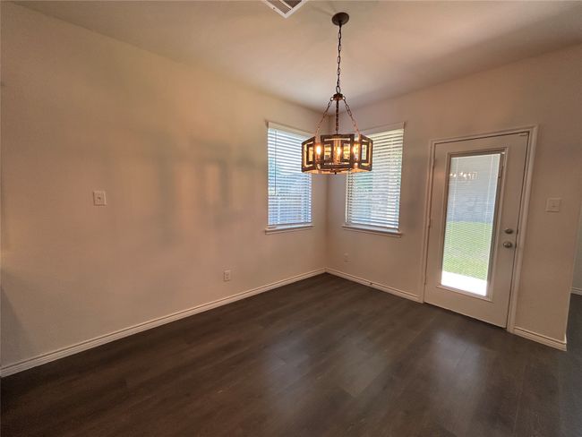 Unfurnished dining area with dark wood finished floors, a chandelier, and baseboards | Image 9