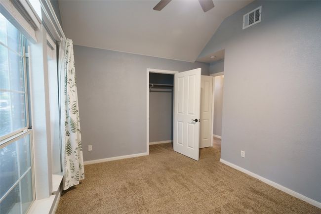 Bedroom with carpet floors, multiple windows, lofted ceiling, a closet, and a ceiling fan | Image 23