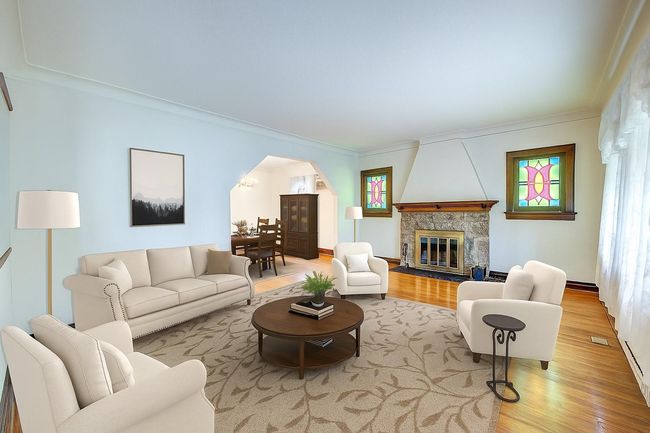 Living area featuring wood finished floors, ornamental molding, arched walkways, and a stone fireplace | Image 6