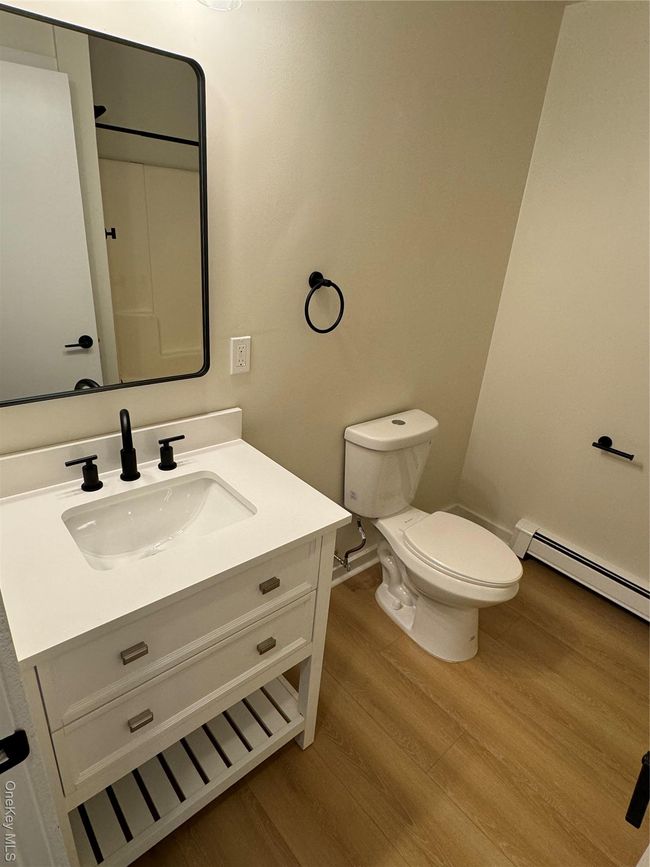 Bathroom with baseboard heating, wood finished floors, and vanity | Image 11