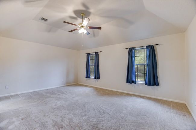 Carpeted spare room with vaulted ceiling, ceiling fan, and baseboards | Image 11
