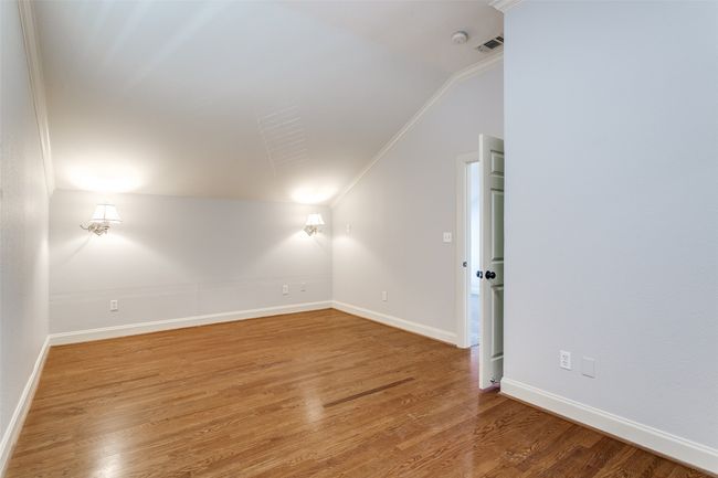 Empty room with vaulted ceiling, wood finished floors, and crown molding | Image 18