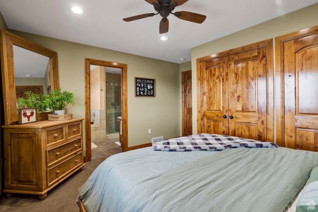 Bedroom featuring ensuite bathroom, visible vents, baseboards, recessed lighting, and dark colored carpet | Image 23