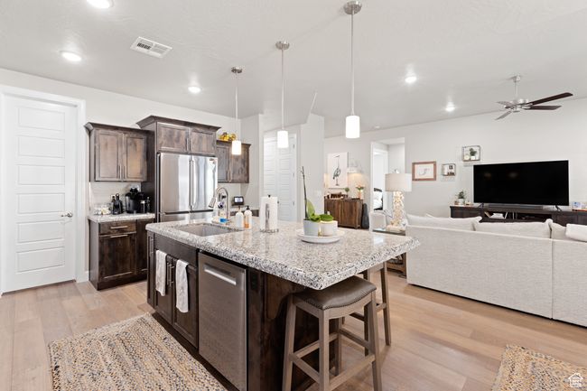 Kitchen with stainless steel appliances, light wood-style floors, dark brown cabinetry, open floor plan, and ceiling fan | Image 46