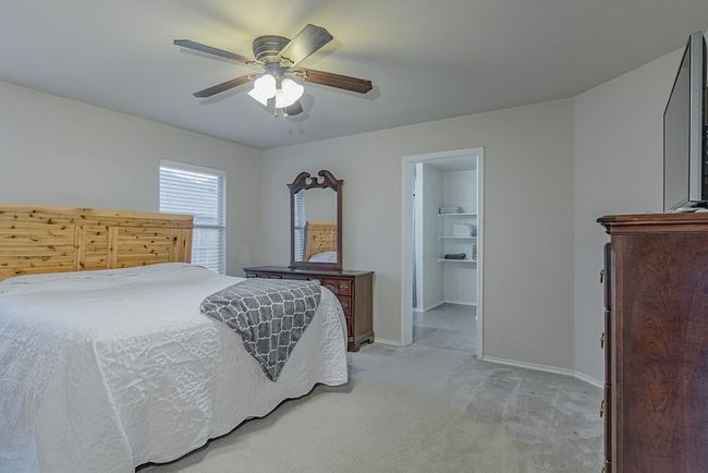 Bedroom with baseboards, ceiling fan, a spacious closet, and light carpet | Image 14