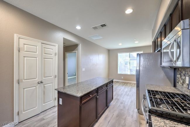 Kitchen with dark brown cabinets, appliances with stainless steel finishes, light wood finished floors, and visible vents | Image 35