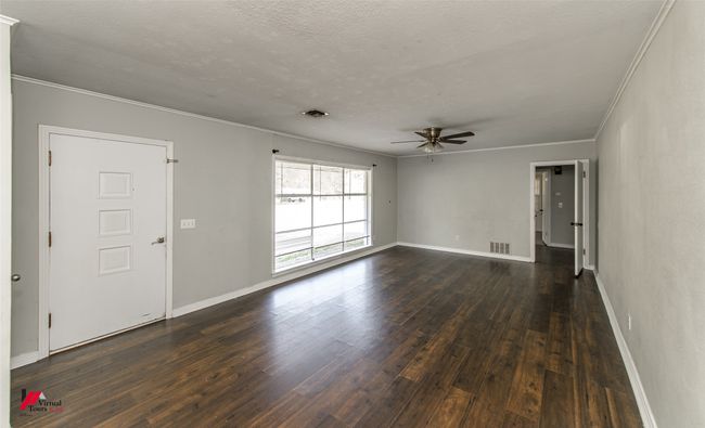 Unfurnished living room featuring baseboards, dark wood-style flooring, crown molding, and a ceiling fan | Image 16