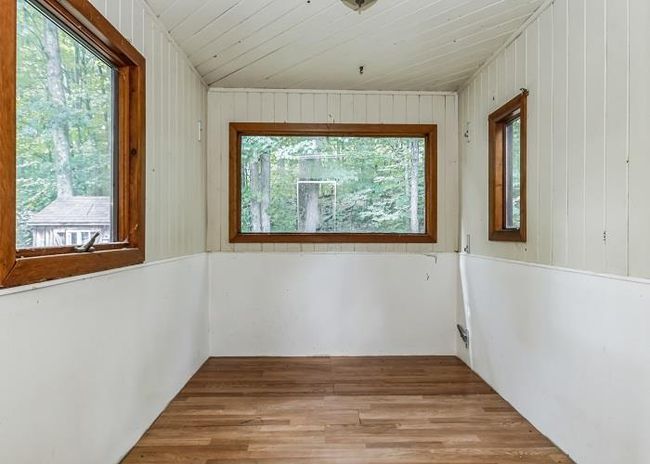 Empty room featuring wood ceiling, wood walls, lofted ceiling, and light hardwood / wood-style flooring | Image 16