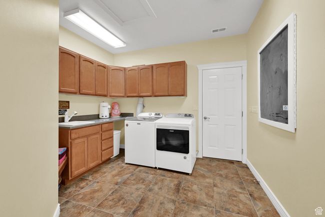 Laundry room with a sink, cabinet space, stone finish floor, visible vents, and washing machine and clothes dryer | Image 33