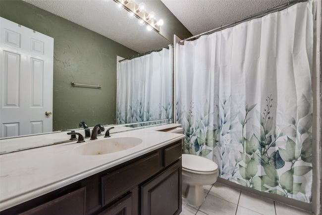 Full bathroom featuring a textured ceiling, vanity, tile patterned flooring, and curtained shower | Image 21