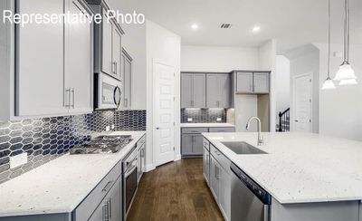 Kitchen with appliances with stainless steel finishes, a center island with sink, dark wood-type flooring, sink, and pendant lighting | Image 3