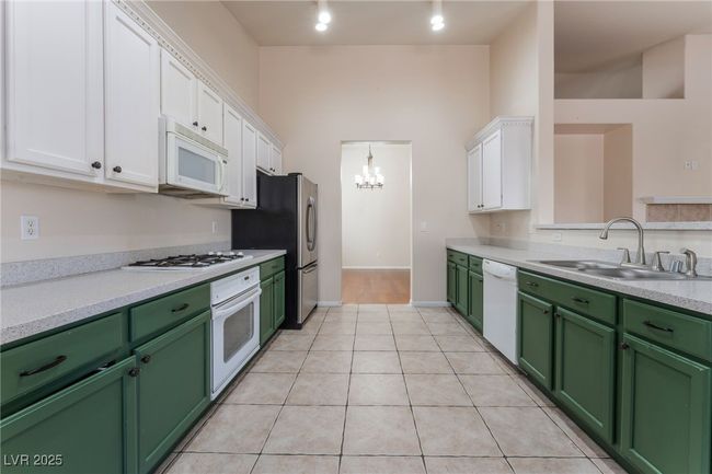 Kitchen with white appliances, green cabinetry, white cabinets, and a sink | Image 14
