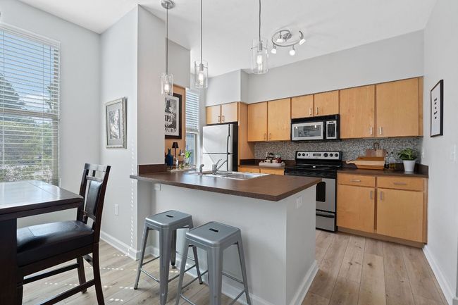Kitchen with stainless steel electric range oven, freestanding refrigerator, dark countertops, and light wood finished floors | Image 9
