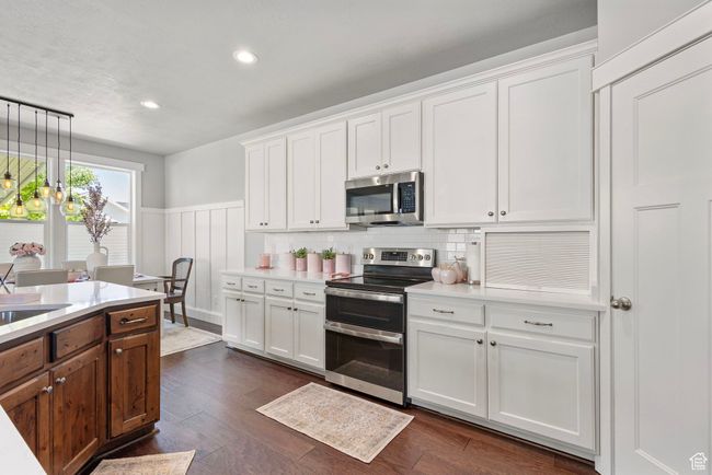 Kitchen featuring appliances with stainless steel finishes, light countertops, a wainscoted wall, white cabinets, and recessed lighting | Image 10