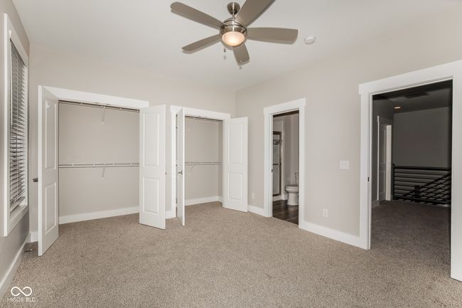unfurnished bedroom featuring carpet, multiple closets, connected bathroom, baseboards, and ceiling fan | Image 4