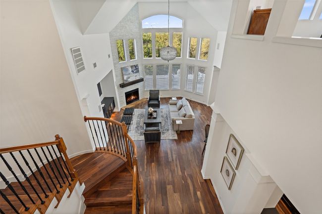 Stairs featuring baseboards, a lit fireplace, high vaulted ceiling, and wood finished floors | Image 23