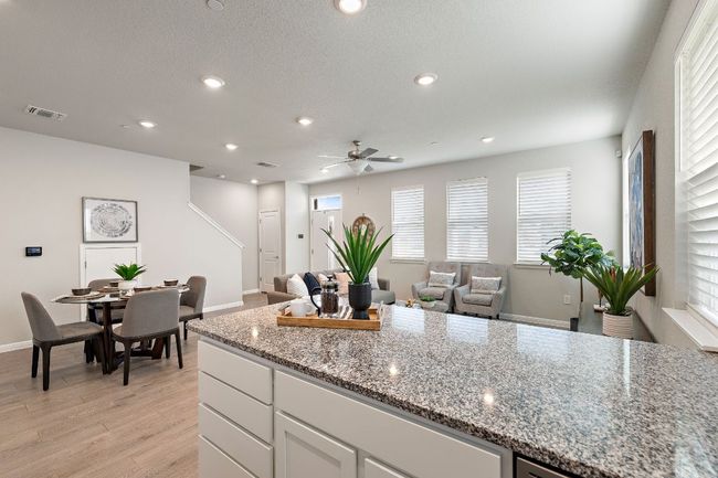 Kitchen with light stone countertops, open floor plan, light wood-type flooring, and ceiling fan | Image 13