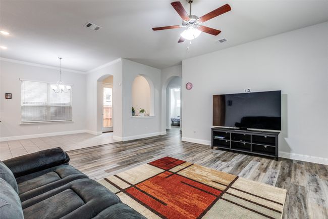 Living room with arched walkways, visible vents, ceiling fan with notable chandelier, and baseboards | Image 9