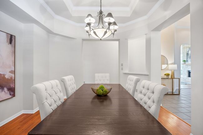 The formal dining room features engineered hardwood flooring and a decorative tray ceiling, adding warmth and character. | Image 17